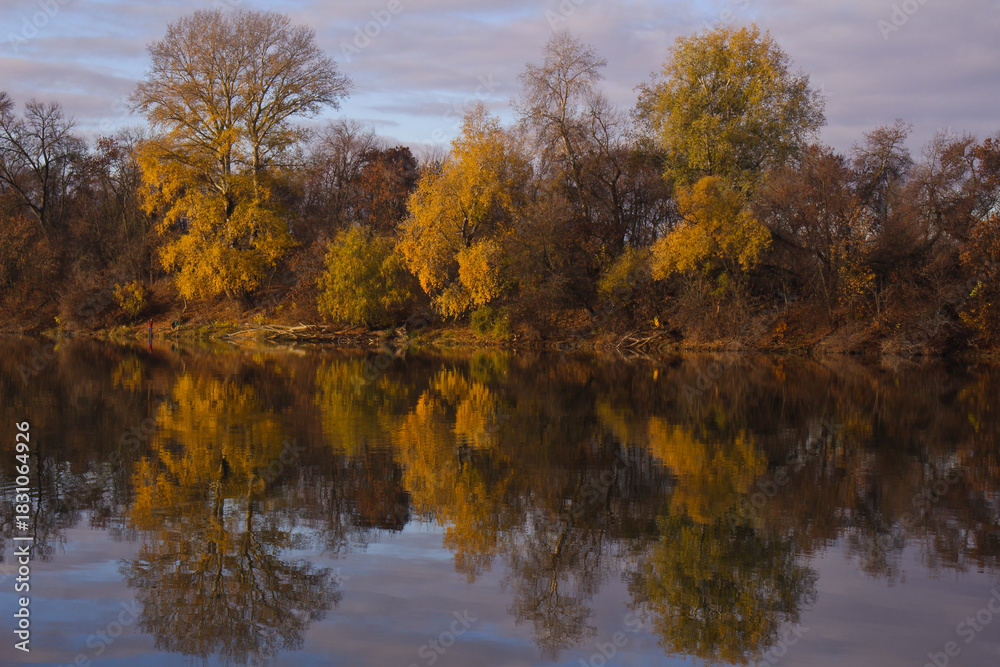 Obraz premium Trees in autumn colors reflected in the water