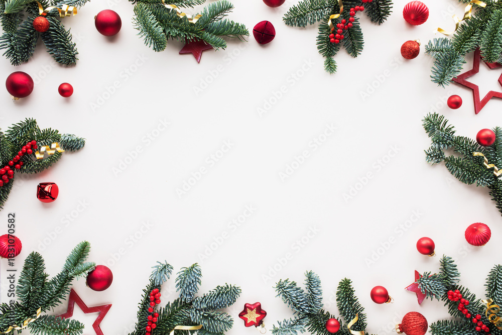 Obraz premium White Christmas background from green fir tree and red ornaments decoration. Festive card frame for celebration top view.
