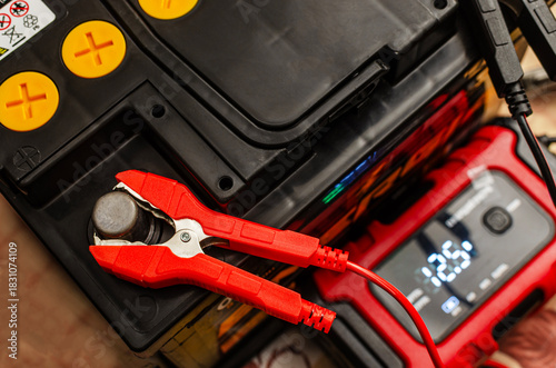 car battery with charger and red clamp on terminal