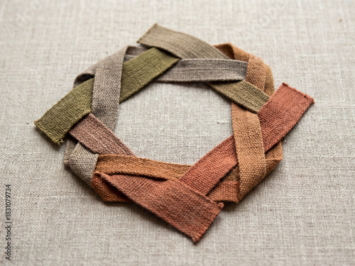 Eco friendly fabric loops forming circular shape on textured linen surface, showcasing natural colors and sustainable textile design with earthy, rustic feel