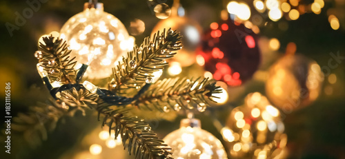 close-up of a Christmas tree adorned with shiny gold and red ornaments, glowing with warm string lights. cozy holiday atmosphere wide banner.