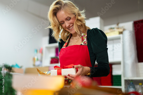 Woman smiling wrapping christmas presents in retail workshop