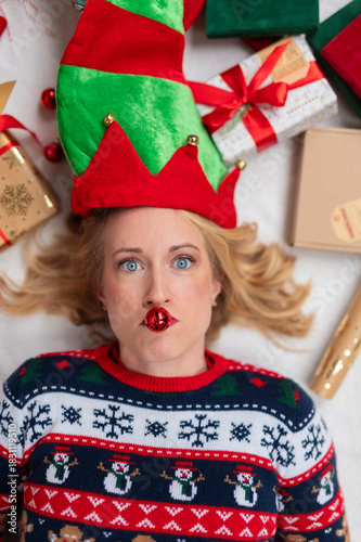 Woman wearing elf hat and ugly christmas sweater with jingle bell
