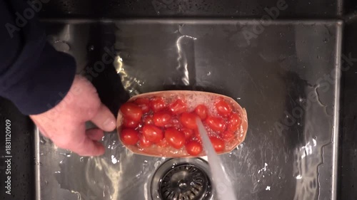 Stockholm, Sweden A cook rinses cherry tomatoes under running water in a sink. 
