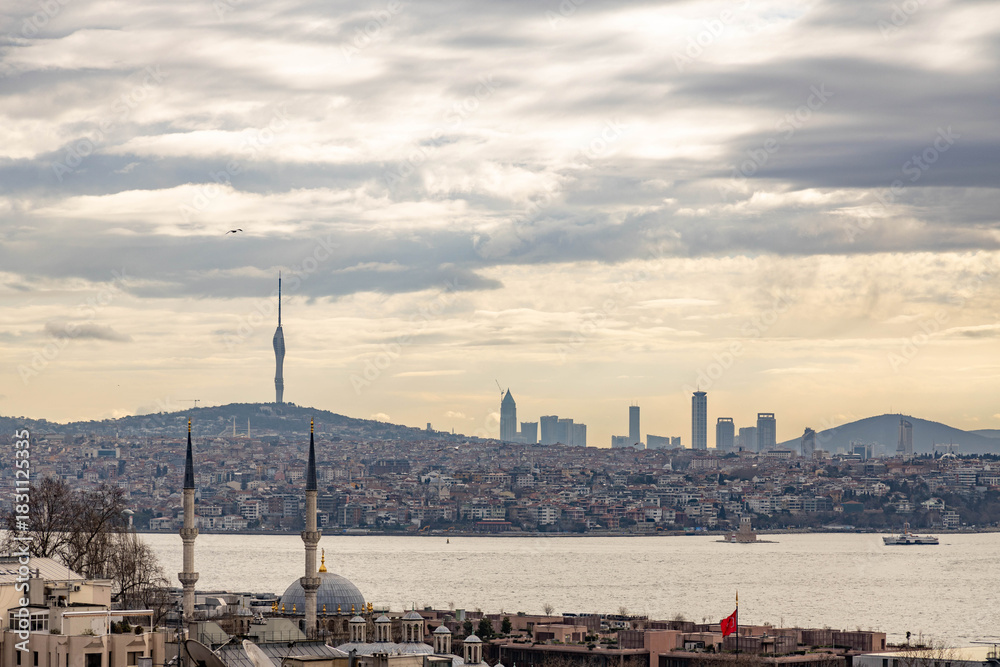 Obraz premium Morning view from a rooftop over Istanbul's European side, showing the Bosphorus with Maiden Tower, Asian shore hills, and Çamlıca Tower in hazy sunrise light. Turkey.