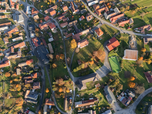 Aerial view of the charming village nestled among vibrant autumn foliage, with red-roofed buildings and winding roads creating a tapestry of color, Hrochot, Banska Bystrica Region, Slovakia.