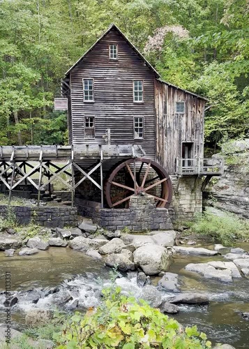 Vertical view of Glade Creek Grist Mill in Babcock State Park, West Virginia beside a flowing creek.