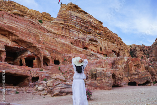 Woman traveling through ancient Petra, Jordan, exploring Nabatean rock cut tombs in a desert landscape