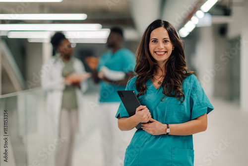 Healthcare professional smiling holding tablet in hospital