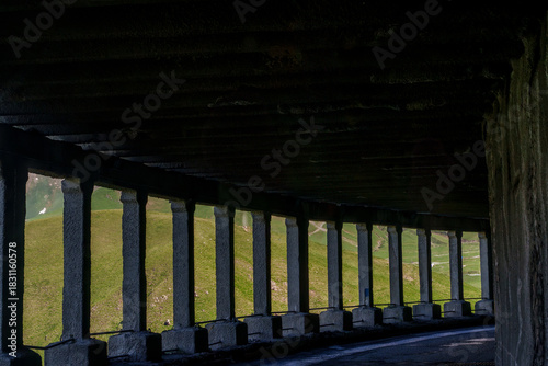Curved mountain road tunnel with repeating concrete pillars and shadows