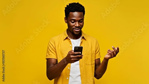 Young black man smiling while using smartphone against yellow background  