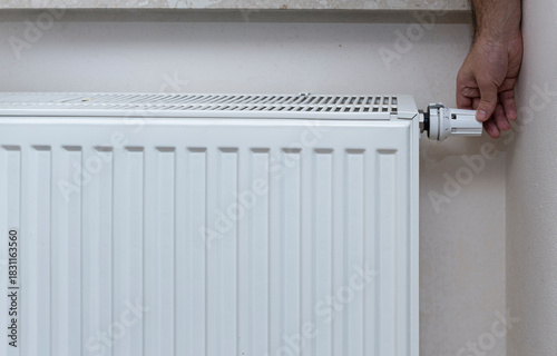 Wallpaper Mural Hand adjusting the thermostat valve on a white radiator in a residential living space, showcasing effective home heating control for comfort and energy efficiency. Torontodigital.ca