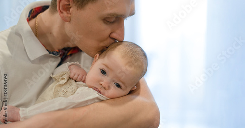 The man gently kisses the baby's head, holding him in his arms