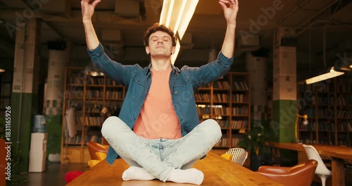 Focused man meditating and levitate on table in modern coworking