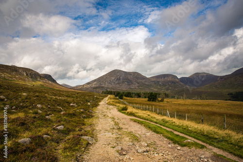 Scenic Gravel Road Winds Through Mountain Valley Under Dramatic Cloudy Sky, Mourne Mountains, Northern Ireland