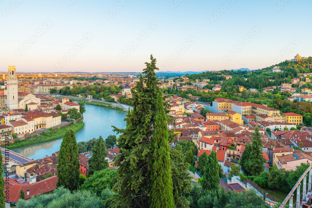 Fototapeta premium Panoramic aerial view of Verona old town with Adige River, terracotta rooftops, cypress trees, Verona Cathedral and colorful buildings at sunset, Veneto, Italy. Italian architecture and cityscape