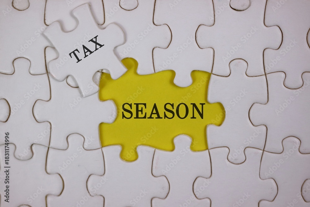 Fototapeta premium Close-up of puzzle pieces, featuring a yellow piece labeled SEASON beside a white piece labeled TAX. Symbolizes the link between tax season and personal or business finances.