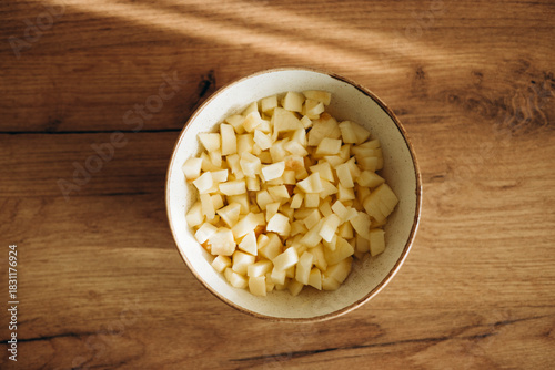 Top view of bowl with diced apples on kitchen table.