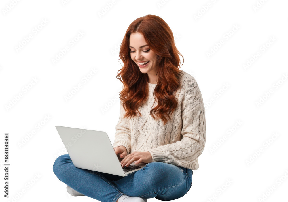 Naklejka premium Smiling young woman with long wavy red hair wearing a cozy cable knit sweater and jeans typing on a laptop isolated on transparent background
