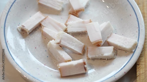 Slicing pork belly fat on wooden board for chinese cooking preparation
