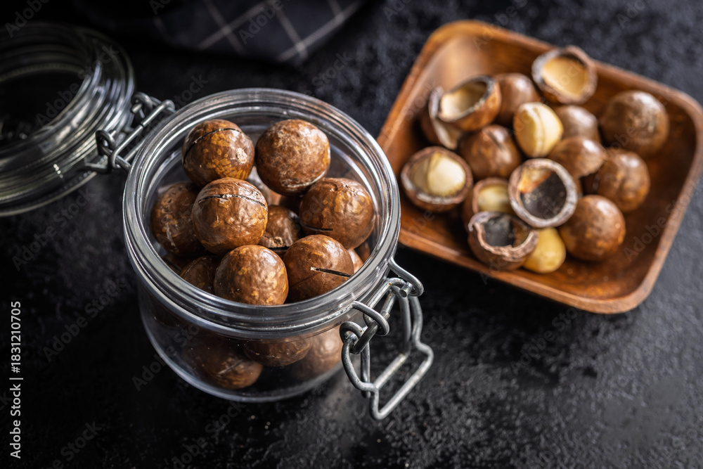 Fototapeta premium Tasty macadamia nuts in jar on black table.