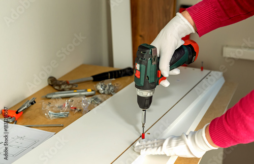 Wallpaper Mural The process of assembling white cabinet furniture using a screwdriver Torontodigital.ca