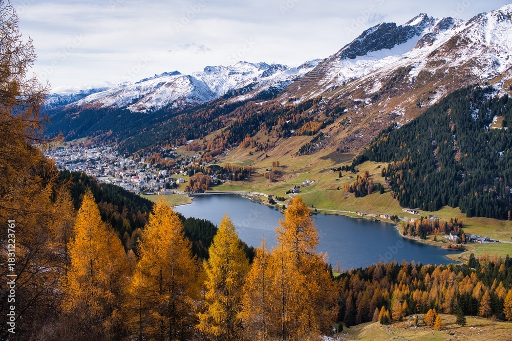 Fototapeta premium Autumnal mountain panorama in Davos with a view of the lake. Majestic Mountain Landscape, Scenic Valley With Colorful Ridges And Peaks, Serene Mountain Vista With Snowcovered Summits Vibrant Meadows