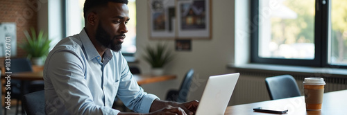 African American man using laptop, browsing Internet in modern office setting, connecting with global world, and getting things done. African American man concentrating,