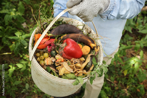 Zero waste, composting, bio waste, separate waste collection concept. Farmer hands with vegetable and fruit food scraps in bucket for compost close up