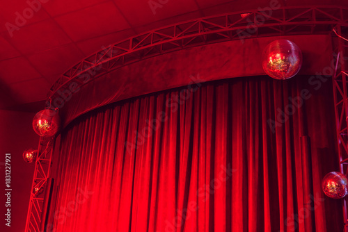 Small stage with red curtains and disco balls in dark red light