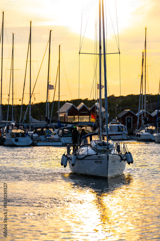 Fototapeta premium Gothenburg, Sweden - July 18 2024: Sailboat entering the harbour at sunset.
