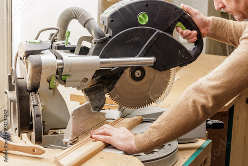 Carpenter cutting wooden board with miter saw during home renovation