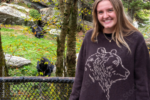 woman smiling by animal enclosure, casual scene showing woman engaging with wildlife conservation
