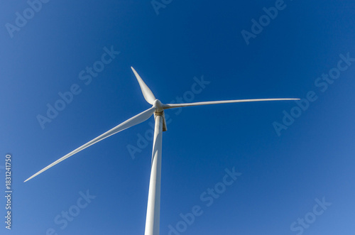 Clean energy wind turbine blue sky horizontal copy space low angle view.