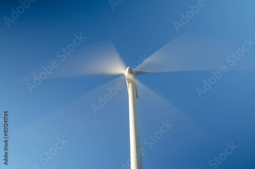 Moving wind turbine blades blurred motion clean energy technology copy space.
