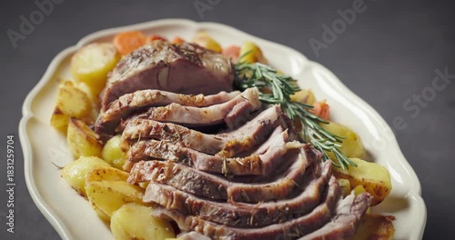 freshly baked pork neck tenderloin and baked potatoes on big white plate, food closeup