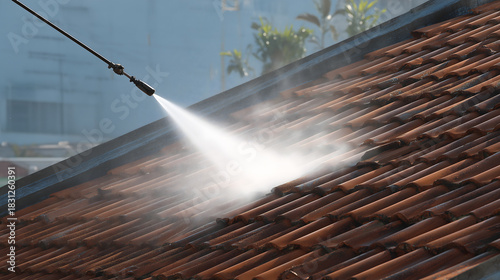 Le nettoyage d'un toit en tuiles avec un nettoyeur haute pression.