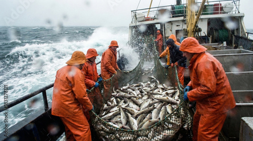 Brave commercial fishermen in orange waterproof gear haul a massive net brimming with fresh fish during a treacherous storm on the rough open sea