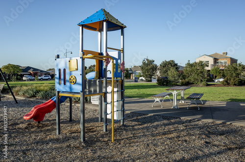 Wallpaper Mural A small neighbourhood playground in Tarneit, Australia, featuring play equipment and nearby picnic tables, within a suburban park, with residential houses in the background. A community outdoor space Torontodigital.ca