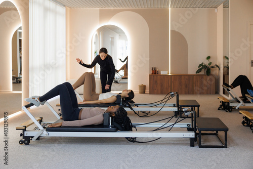 Trainer showing woman how to do exercise during class in gym
