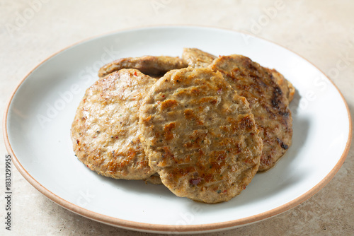 A view of a pile of chicken sausage patties, on a plate.