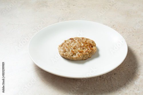 A view of a single chicken sausage patty, on a plate.