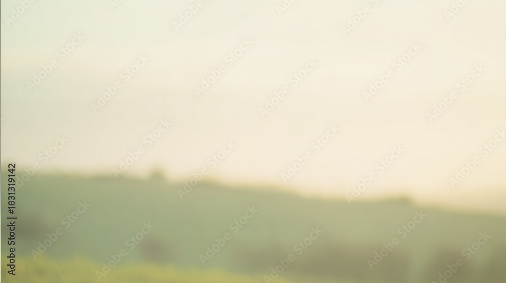 Fototapeta premium A soft, blurred landscape depicting rolling hills under a gentle sunrise, evoking a serene and tranquil atmosphere.