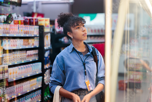 Woman browsing refrigerated section in a convenience store.