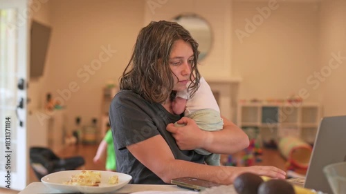 tired caregiver momentarily relaxes with infant, overwhelmed guardian takes quick break while holding infant, fatigued mother or father gently pauses to gather strength amidst busy household