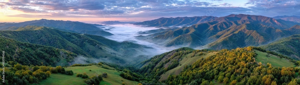 Fototapeta premium A misty mountain range beneath cloudy sky concept. A breathtaking view of rolling hills covered in lush greenery.