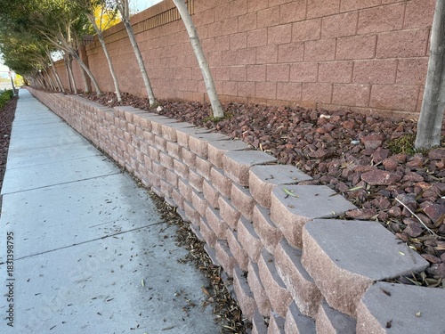 Desert Red Stone Retaining Wall: Landscaped retaining wall built with red bricks and natural red rocks in a suburb.