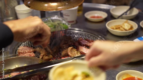 Close-up of Hand Grilling Pork Belly (Samgyeopsal) Causing a Flare-up on K-BBQ Grill, Meat Cooking Over Intense Heat and Fire, Authentic Korean Food Experience