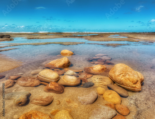 Rocky coastline, shallow pools, and clear blue sky