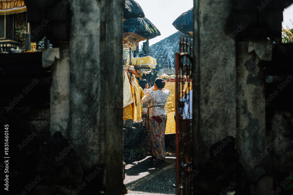 Obraz premium Balinese women offering incense and ceremonial items at temple